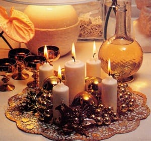 Gilded Splendour. Quite ordinary objects can be grouped around inexpensive candles to create an eye-catching table or seasonal decoration. These squat, white candles, arranged on a golden doily make a glittering display to complement the gold goblets. With safety in mind, it is important to remember to snuff out all the candles before they burn down to the bottom of the wick.